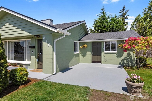 626 Legion Dr, Everett, WA 98201 - view of front of home with a chimney, a shingled roof, concrete block siding, and a patio area