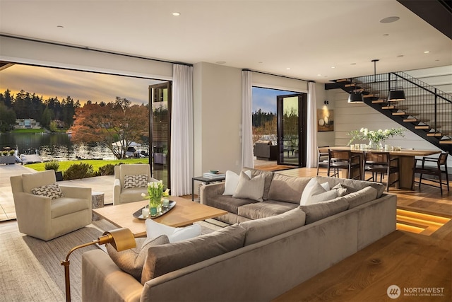 living room with stairs, a water view, and wood finished floors