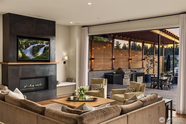 living area with a healthy amount of sunlight, a glass covered fireplace, recessed lighting, and wood finished floors