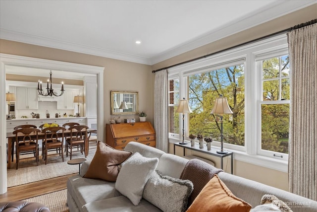 living area featuring crown molding, wood finished floors, an inviting chandelier, and a healthy amount of sunlight