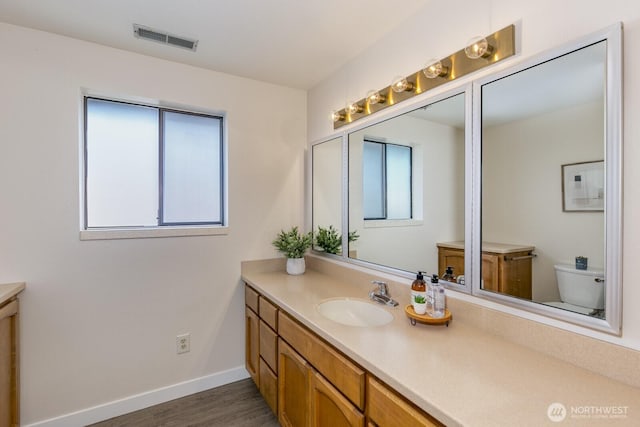 200 Priest Point Dr NE, Tulalip, WA 98271 - bathroom with toilet, baseboards, visible vents, vanity, and wood finished floors