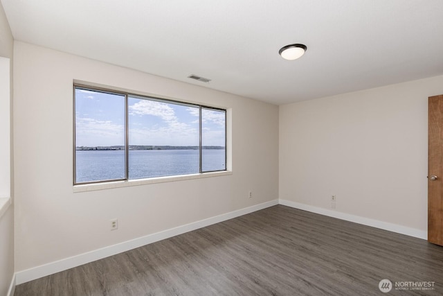 200 Priest Point Dr NE, Tulalip, WA 98271 - empty room with a water view, baseboards, visible vents, and wood finished floors