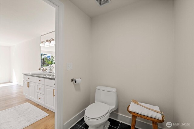 bathroom featuring visible vents, vanity, wood finished floors, toilet, and baseboards