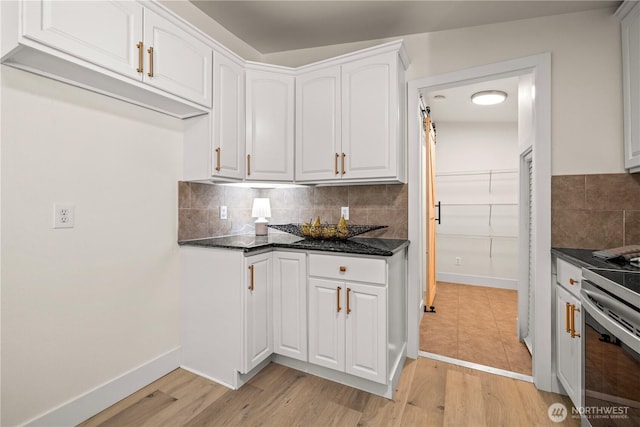 kitchen featuring decorative backsplash, baseboards, white cabinetry, light wood-style flooring, and stainless steel range with electric cooktop