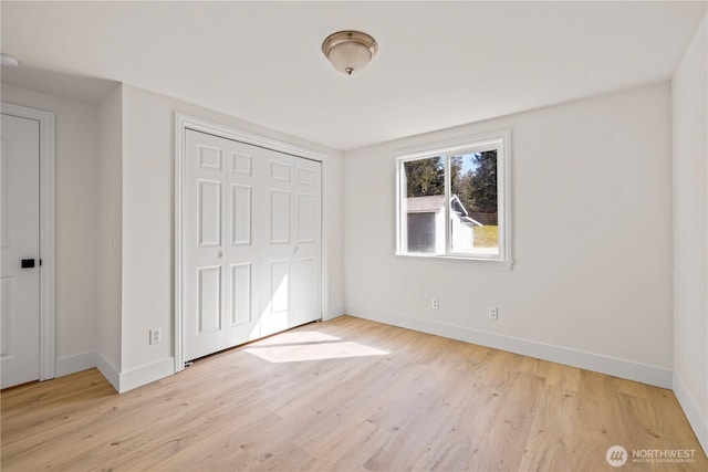 unfurnished bedroom with baseboards, a closet, and light wood-type flooring