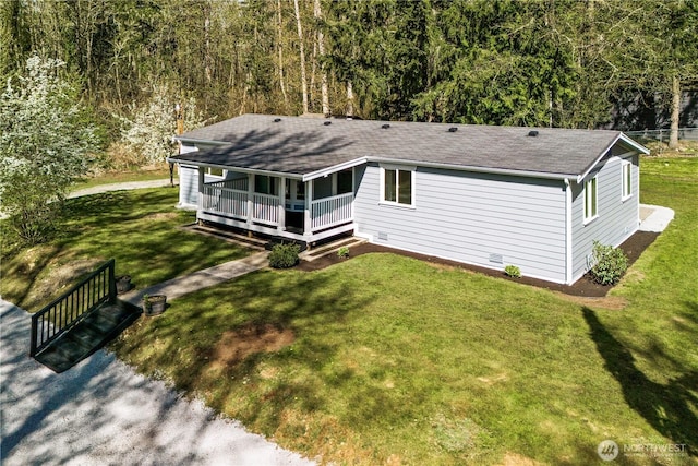 exterior space with roof with shingles, covered porch, a front yard, and a forest view