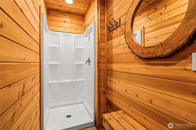 bathroom with wood walls and a stall shower