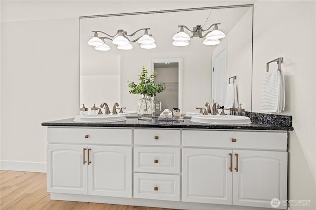 bathroom with double vanity, a sink, baseboards, and wood finished floors