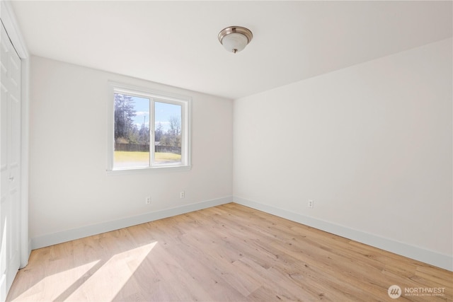 spare room featuring baseboards and wood finished floors
