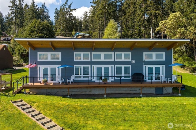 back of property with a lawn, french doors, and a deck