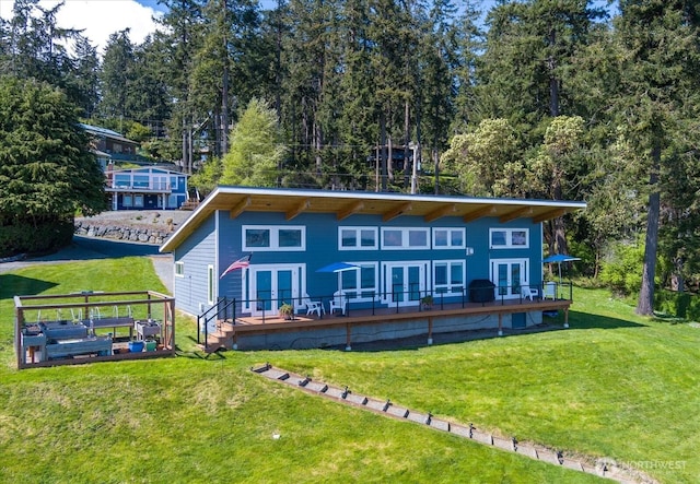 back of property with a yard, french doors, and a wooden deck