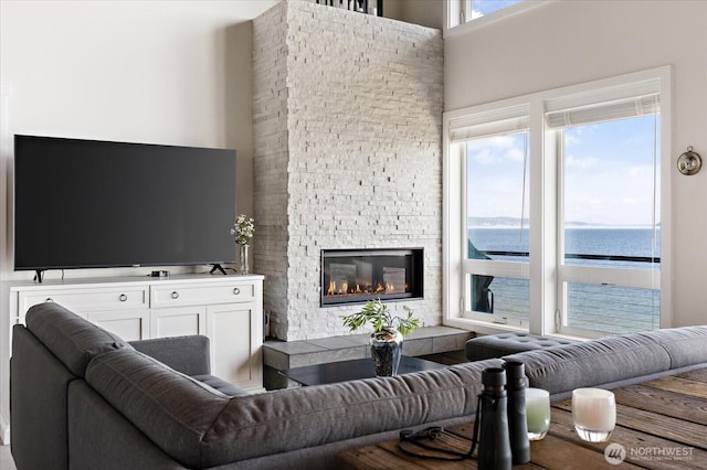 living room with a towering ceiling, a water view, and a fireplace