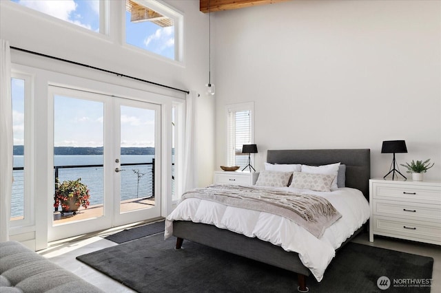 bedroom with a high ceiling, multiple windows, access to outside, a water view, and french doors
