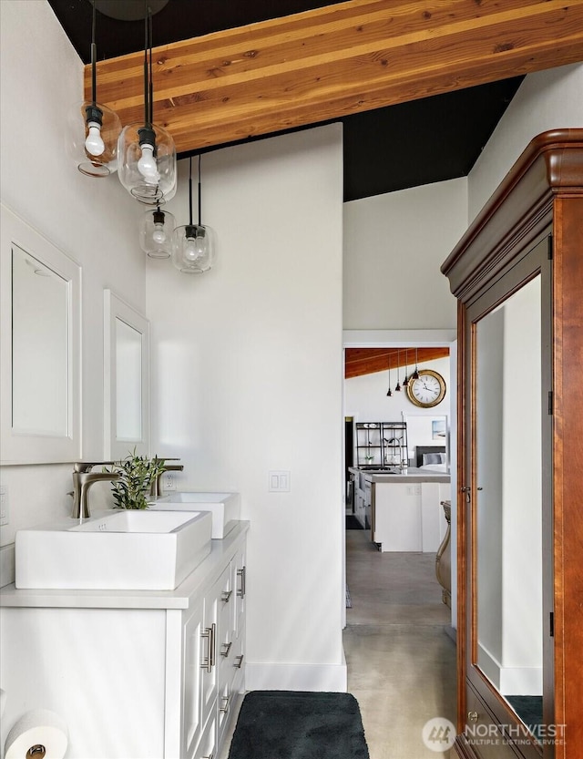 bathroom featuring double vanity, a sink, and baseboards