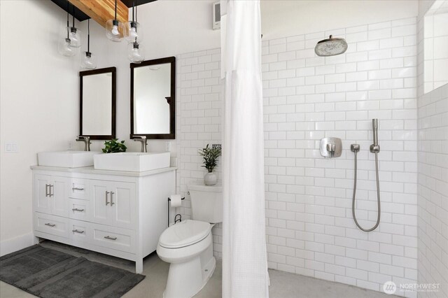 full bathroom featuring double vanity, toilet, a tile shower, and a sink