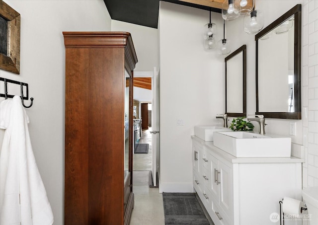 bathroom featuring a sink, baseboards, and double vanity