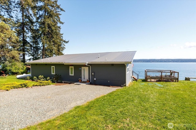 single story home with a water view, driveway, a front lawn, and metal roof