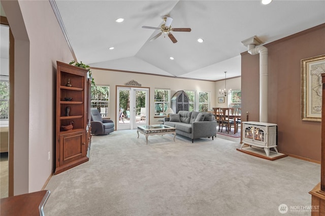 carpeted living area featuring lofted ceiling, recessed lighting, a wood stove, and ceiling fan with notable chandelier