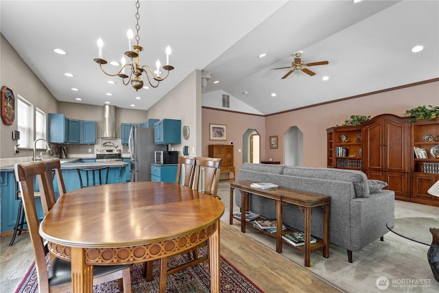 dining area with vaulted ceiling, ceiling fan with notable chandelier, light wood-style floors, arched walkways, and recessed lighting