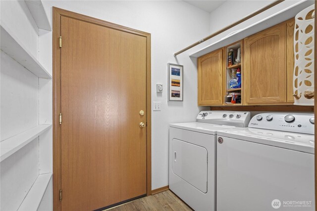 laundry area featuring washing machine and dryer, cabinet space, and light wood-style floors
