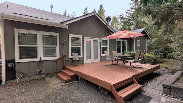 back of house with a wooden deck, french doors, roof with shingles, and outdoor dining space