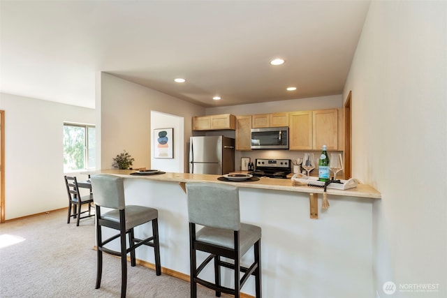382 NE Ohenry Ct, Poulsbo, WA 98370 - kitchen featuring recessed lighting, light brown cabinetry, stainless steel appliances, a peninsula, and a kitchen bar