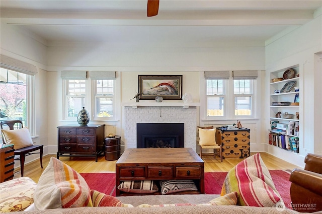 living room featuring a fireplace, wood finished floors, a wealth of natural light, and beam ceiling