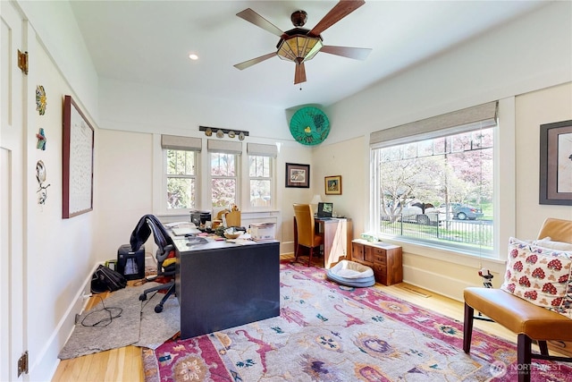 office space with baseboards, a ceiling fan, wood finished floors, and a healthy amount of sunlight