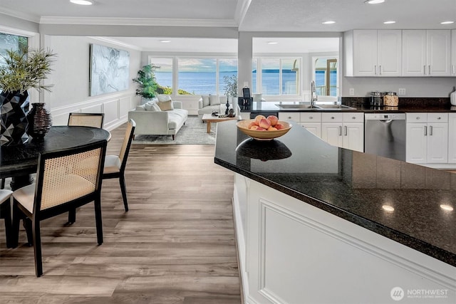 8001 Talbot Rd, Edmonds, WA 98026 - kitchen featuring stainless steel dishwasher, ornamental molding, light wood finished floors, white cabinetry, and healthy amount of natural light