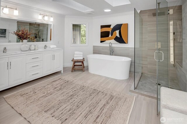 8001 Talbot Rd, Edmonds, WA 98026 - bathroom featuring a skylight, ornamental molding, a stall shower, double vanity, and a freestanding tub
