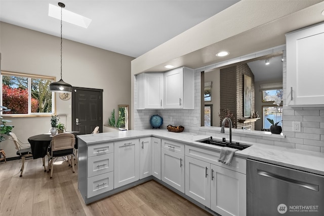 7340 Steilacoom Blvd SW, Lakewood, WA 98499 - kitchen with a skylight, stainless steel dishwasher, a sink, white cabinetry, and a peninsula