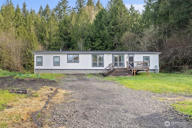 manufactured / mobile home featuring a wooded view, a front yard, and crawl space