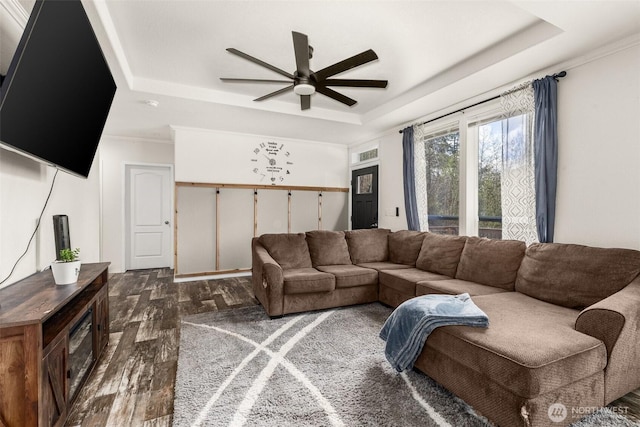 living area featuring crown molding, ceiling fan, visible vents, wood finished floors, and a raised ceiling