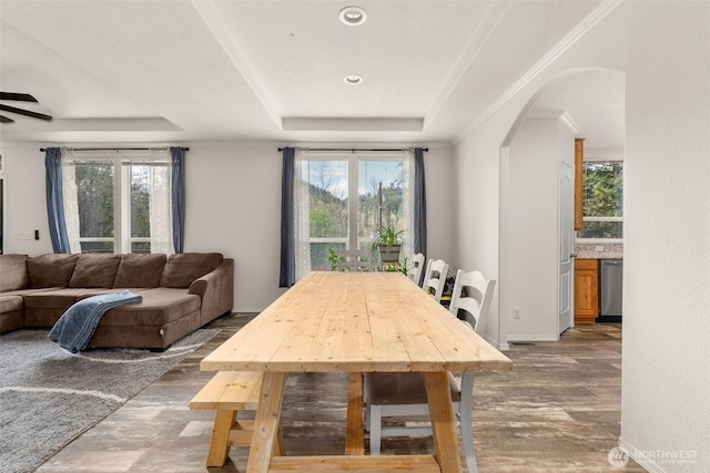dining area with baseboards, recessed lighting, a tray ceiling, arched walkways, and wood finished floors