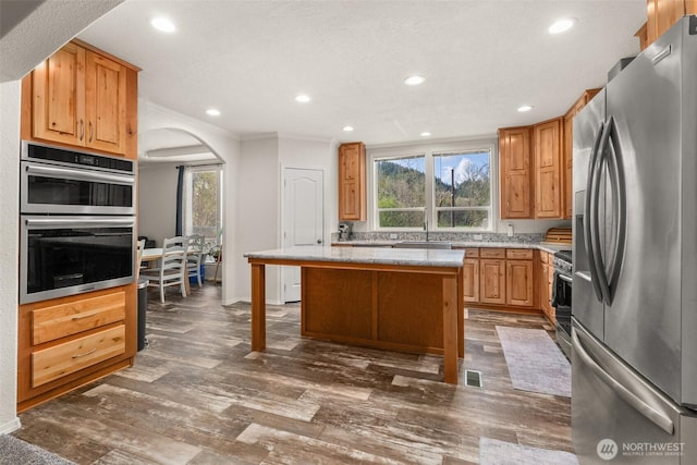 kitchen with stainless steel appliances, arched walkways, plenty of natural light, and recessed lighting