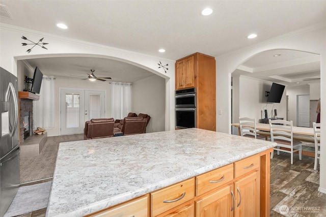 kitchen featuring open floor plan, ceiling fan, arched walkways, and stainless steel appliances