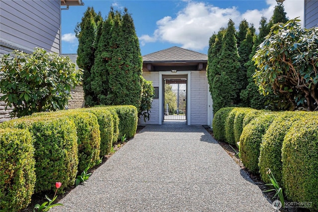 entrance to property with brick siding and roof with shingles