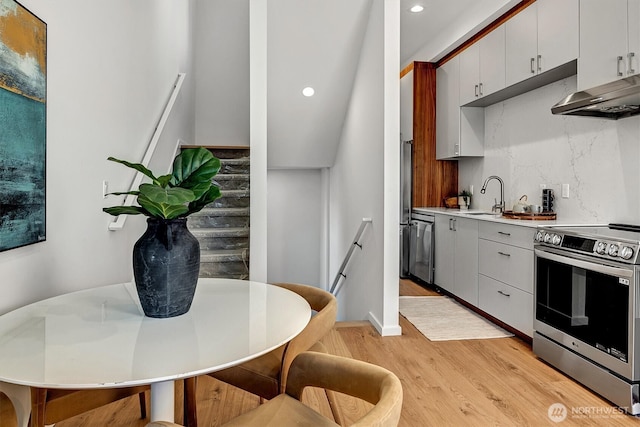 1233 E Roy St, Seattle, WA 98102 - kitchen with light wood-type flooring, recessed lighting, wall chimney exhaust hood, appliances with stainless steel finishes, and a sink