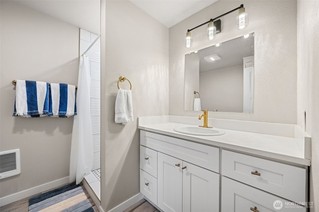 34 4th St S, Pacific Beach, WA 98571 - bathroom featuring a shower with shower curtain, vanity, baseboards, heating unit, and wood finished floors