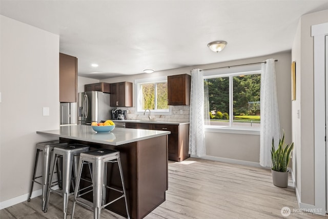 34 4th St S, Pacific Beach, WA 98571 - kitchen with a breakfast bar, a peninsula, light countertops, stainless steel refrigerator with ice dispenser, and decorative backsplash