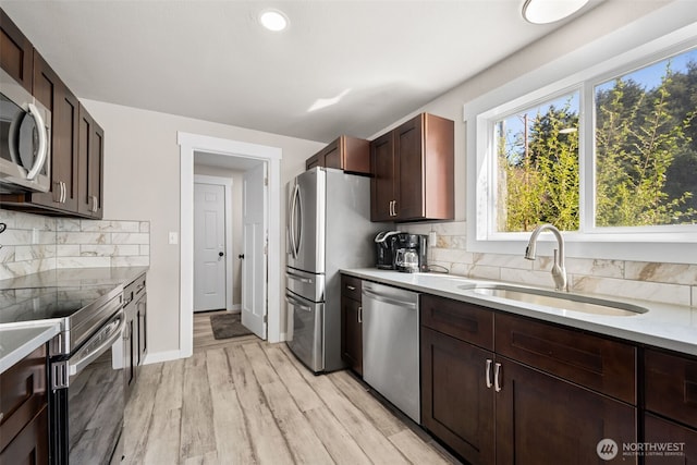 34 4th St S, Pacific Beach, WA 98571 - kitchen featuring light wood-style floors, tasteful backsplash, light countertops, a sink, and stainless steel appliances