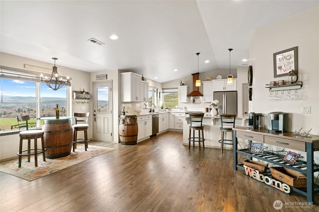 461 Deer Valley Dr, Ellensburg, WA 98926 - interior space with a kitchen breakfast bar, wall chimney range hood, white cabinets, visible vents, and appliances with stainless steel finishes