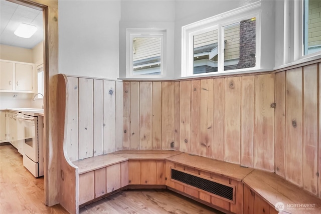 mudroom featuring light wood finished floors, wooden walls, and a wainscoted wall