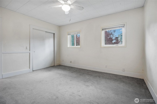 unfurnished bedroom featuring carpet, baseboards, a closet, and a ceiling fan