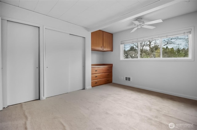 unfurnished bedroom featuring light carpet and two closets