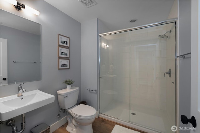 full bath featuring a sink, a shower stall, toilet, and visible vents