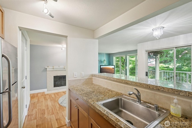 300 N 130th St Unit 8302, Seattle, WA 98133 - kitchen featuring freestanding refrigerator, a sink, light wood-style flooring, a tile fireplace, and brown cabinets