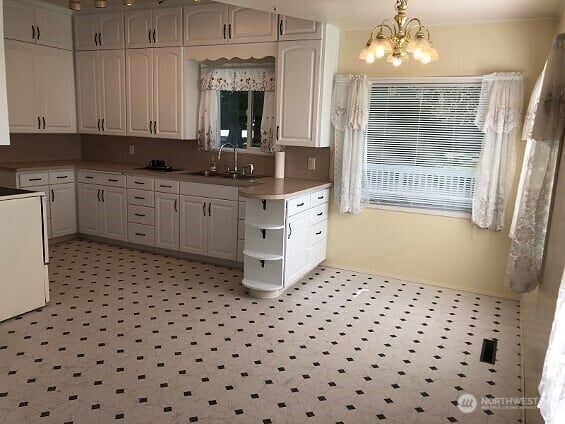kitchen featuring a sink, open shelves, white cabinets, and a notable chandelier