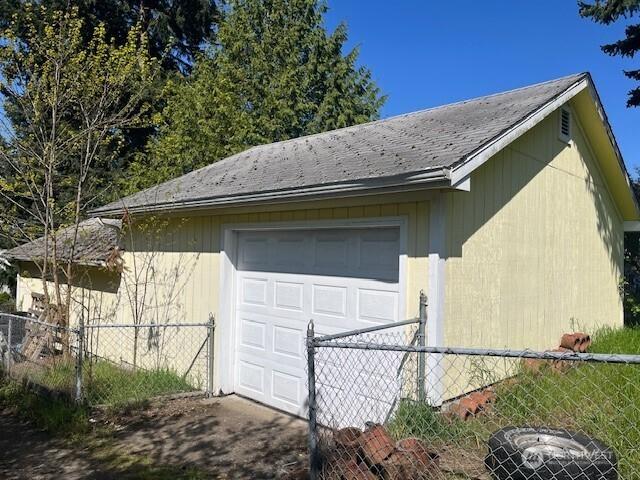 view of side of property featuring driveway, a garage, fence, and an outdoor structure