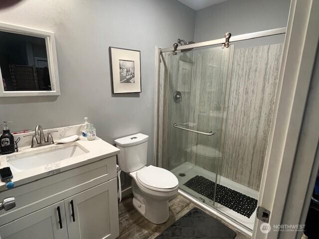 full bathroom with toilet, a stall shower, wood finished floors, and vanity